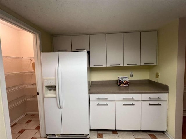 kitchen with white refrigerator with ice dispenser and a textured ceiling