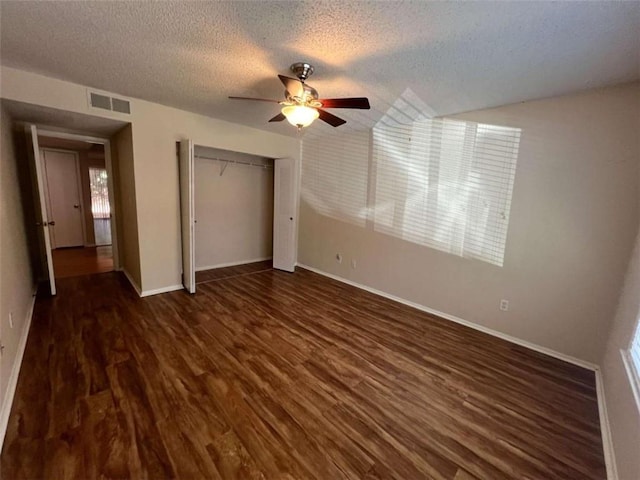 unfurnished bedroom with a textured ceiling, dark hardwood / wood-style floors, a closet, and ceiling fan