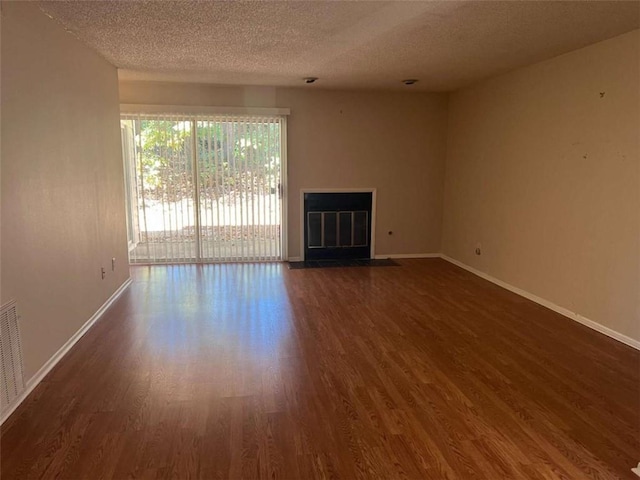 empty room with dark wood-type flooring and a textured ceiling