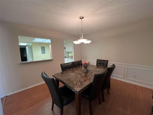 dining area with a textured ceiling, electric panel, and hardwood / wood-style flooring