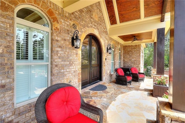 property entrance featuring covered porch, brick siding, and a ceiling fan