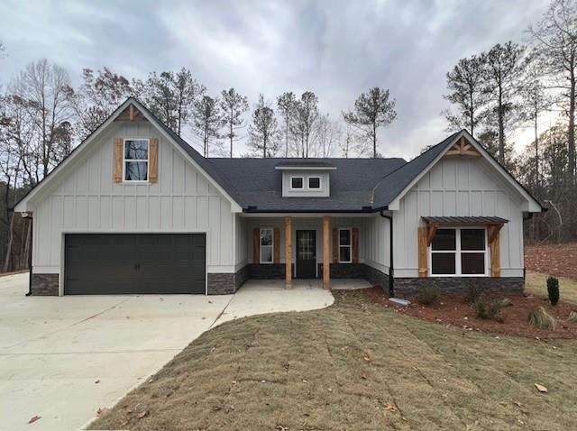 modern farmhouse featuring a porch, a front yard, and a garage