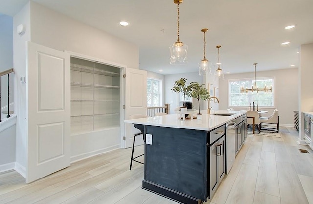 kitchen featuring sink, an island with sink, a chandelier, and decorative light fixtures