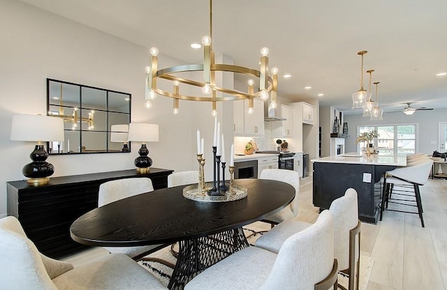 dining space featuring ceiling fan with notable chandelier, sink, and light hardwood / wood-style floors