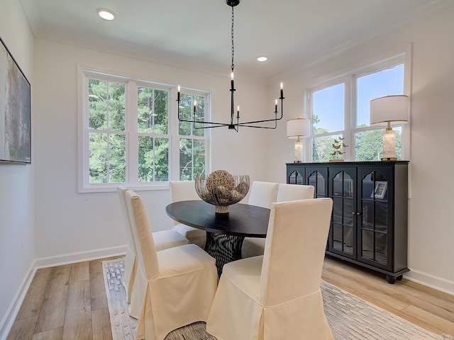 dining space with light hardwood / wood-style floors, a wealth of natural light, and a chandelier