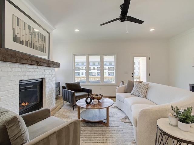 living room with a brick fireplace, hardwood / wood-style floors, ornamental molding, and ceiling fan