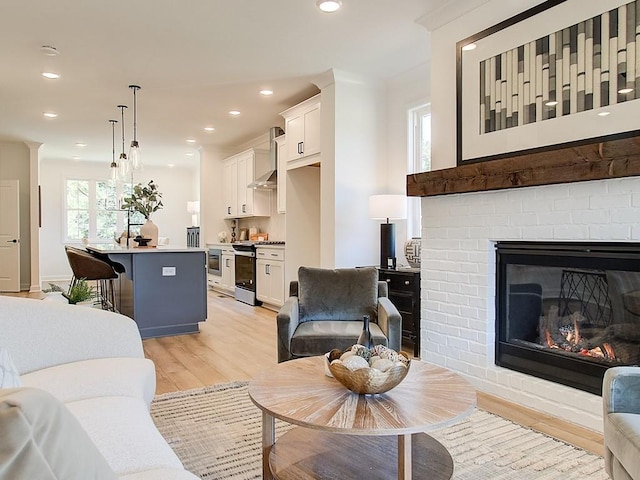 living room featuring a brick fireplace and light hardwood / wood-style floors