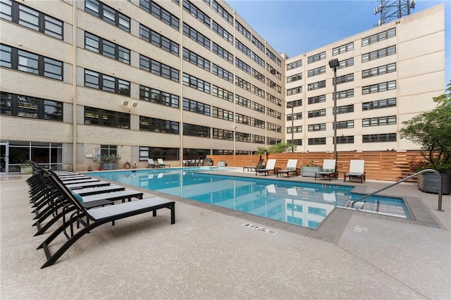 community pool with a patio and fence