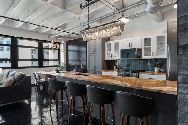kitchen with stainless steel appliances, a sink, wooden counters, tasteful backsplash, and a kitchen breakfast bar