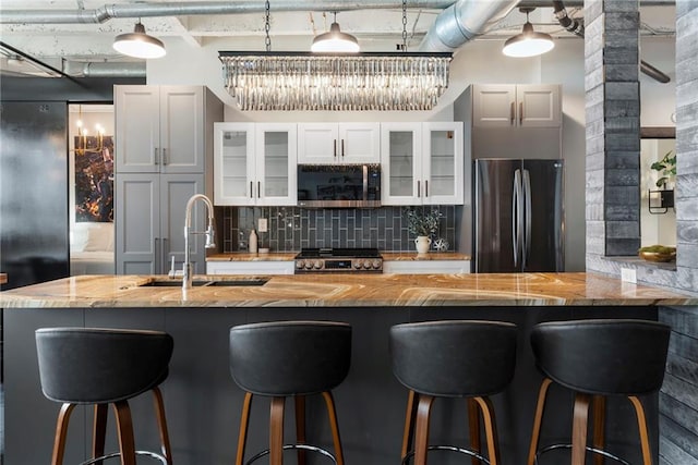 kitchen featuring freestanding refrigerator, stainless steel microwave, a sink, stove, and tasteful backsplash
