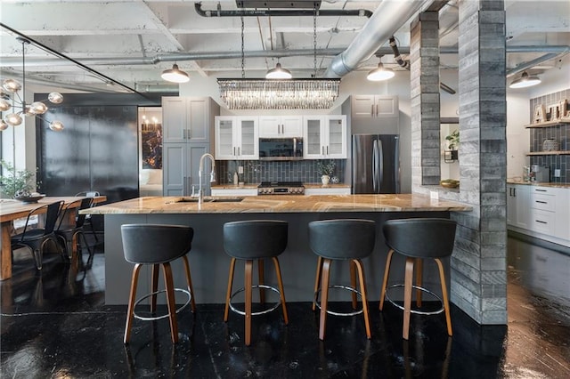 kitchen featuring freestanding refrigerator, stainless steel microwave, tasteful backsplash, a sink, and glass insert cabinets