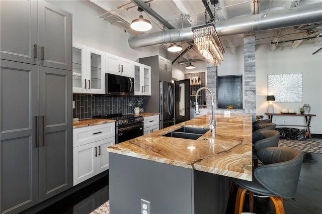 kitchen with a sink, black electric range, freestanding refrigerator, a breakfast bar area, and decorative backsplash
