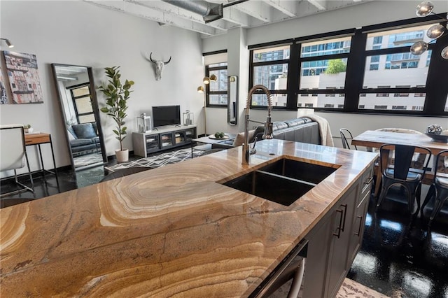 kitchen with a sink, light stone counters, and open floor plan