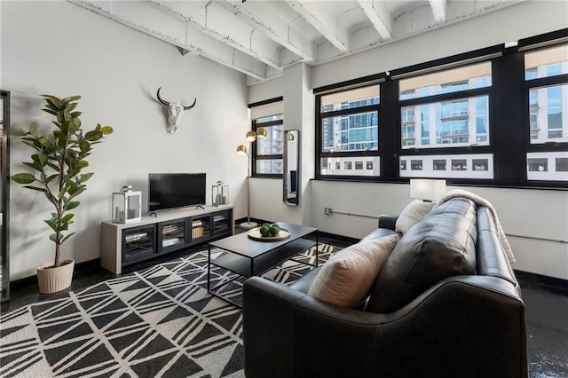 living area featuring healthy amount of natural light, beamed ceiling, and baseboards