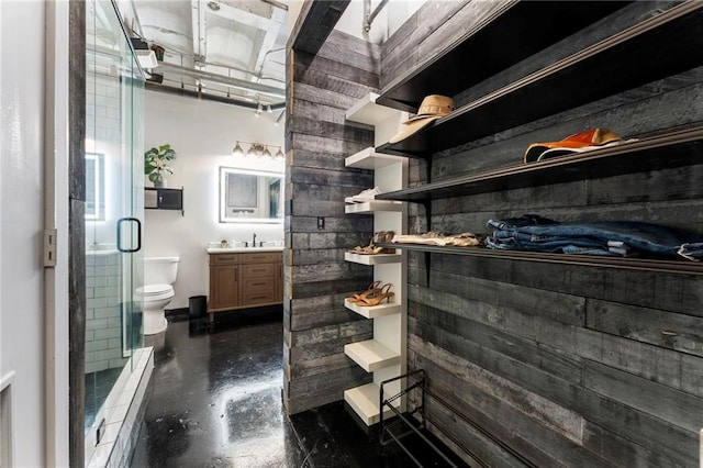 full bathroom featuring concrete flooring, a stall shower, toilet, and vanity