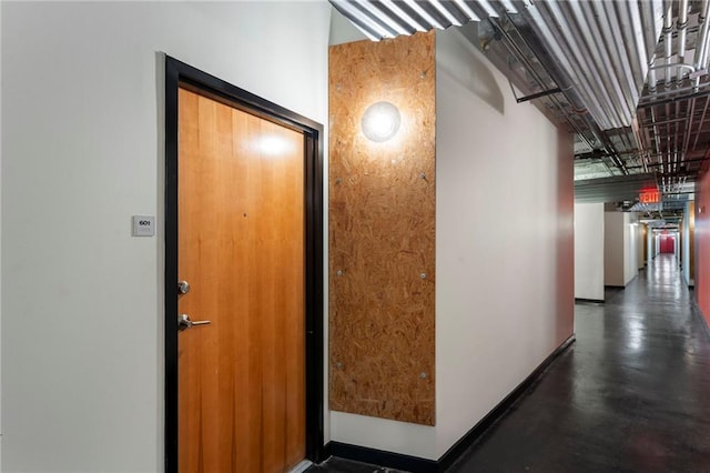 corridor featuring baseboards and finished concrete floors