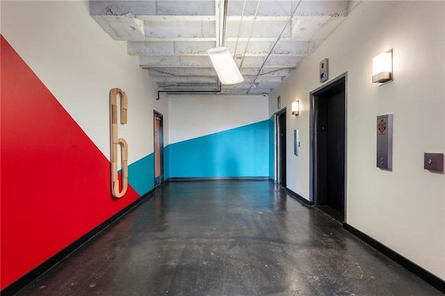 corridor featuring elevator and baseboards