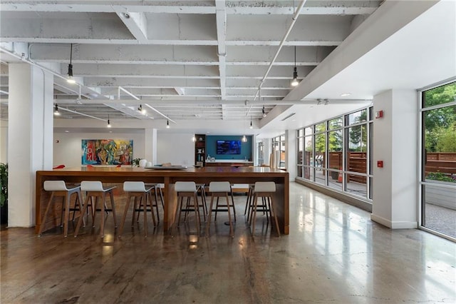 indoor dry bar featuring baseboards and finished concrete floors