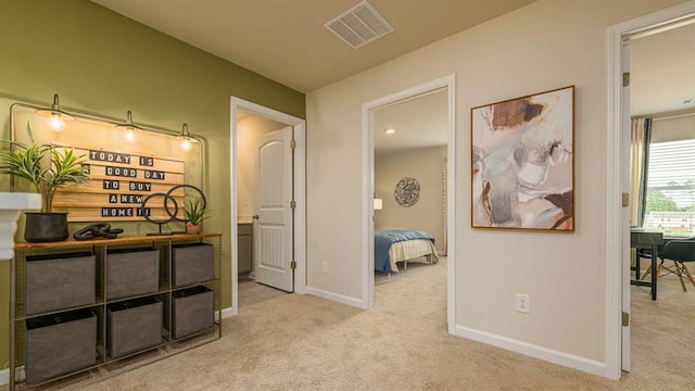 hall with carpet flooring, visible vents, and baseboards