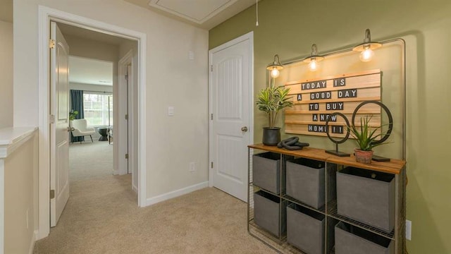 corridor with light carpet, attic access, and baseboards