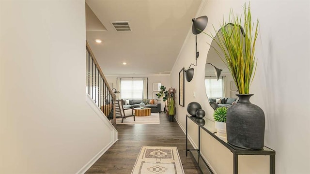 foyer with dark wood-style floors, crown molding, visible vents, stairway, and baseboards