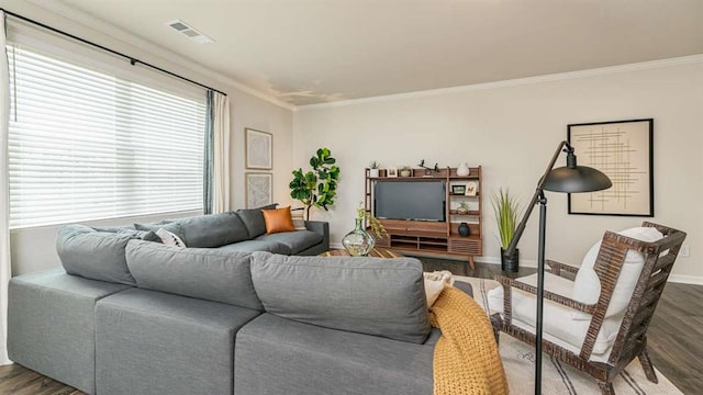 living area with baseboards, wood finished floors, visible vents, and crown molding