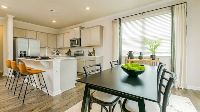 kitchen with stainless steel appliances, a kitchen island with sink, crown molding, and visible vents