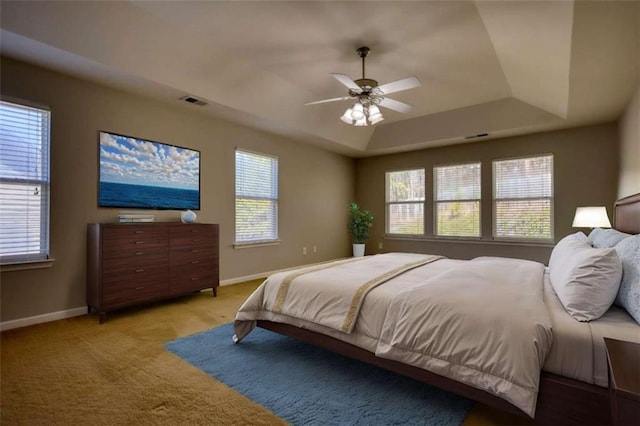 carpeted bedroom featuring ceiling fan and a tray ceiling