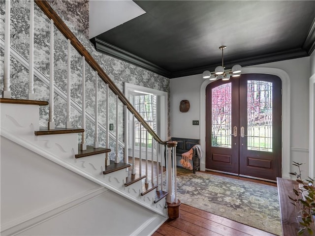 foyer featuring wood-type flooring, stairs, a chandelier, french doors, and arched walkways
