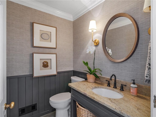 half bathroom featuring crown molding, vanity, toilet, a wainscoted wall, and visible vents