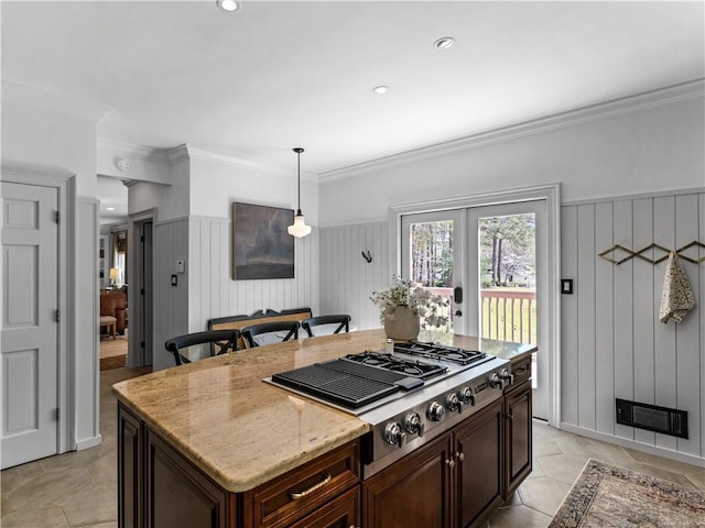 kitchen featuring a kitchen island, decorative light fixtures, crown molding, light stone countertops, and stainless steel gas stovetop