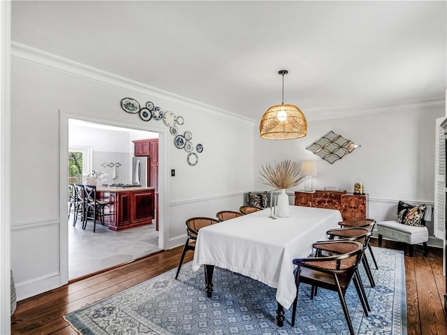 dining area featuring wood-type flooring, baseboards, and crown molding