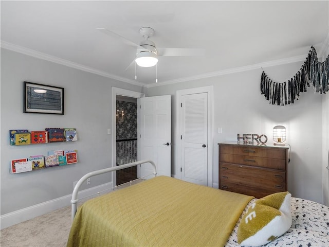 carpeted bedroom with crown molding, a ceiling fan, baseboards, and a closet