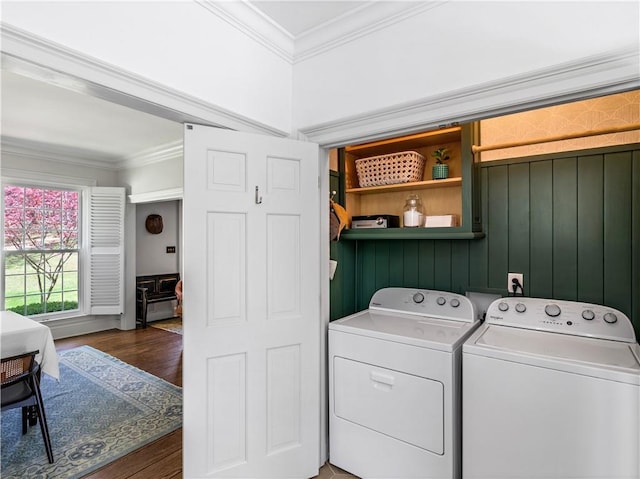 clothes washing area featuring laundry area, crown molding, wood finished floors, and washing machine and clothes dryer
