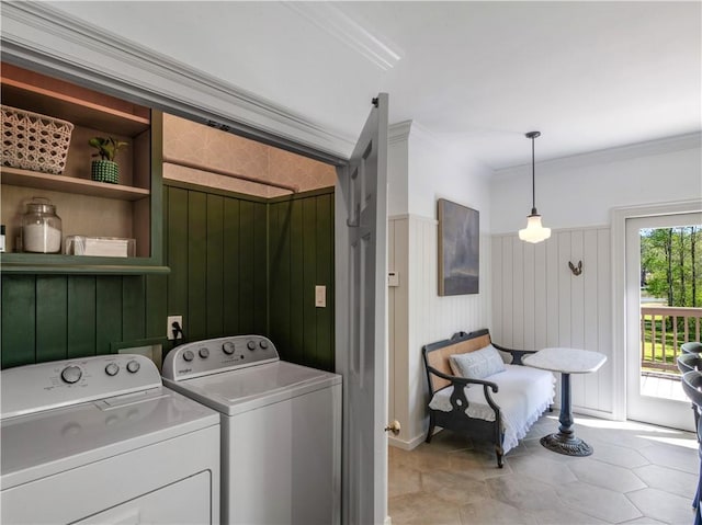 clothes washing area featuring crown molding, light tile patterned floors, washing machine and dryer, and a wainscoted wall