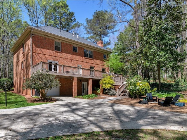 view of front of home with stairway, brick siding, a wooden deck, and a chimney
