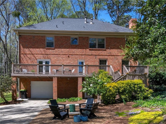 rear view of property with a garage, driveway, a deck, and brick siding
