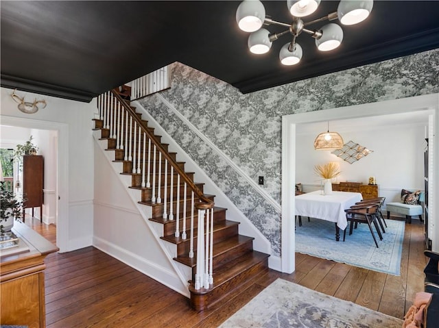 stairway with wood-type flooring, baseboards, a chandelier, and crown molding