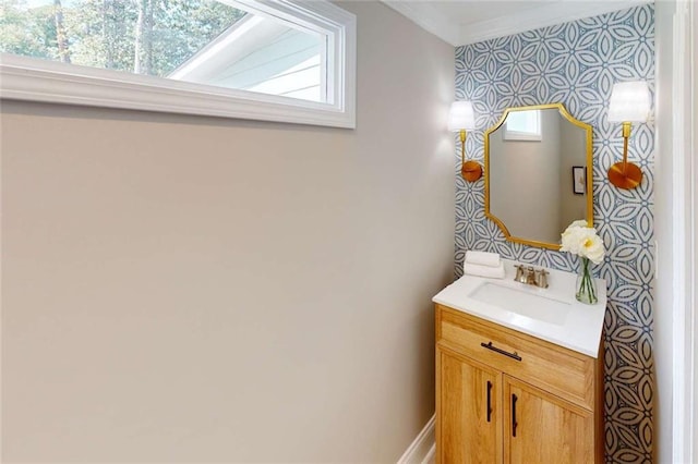 bathroom with wallpapered walls, crown molding, and vanity