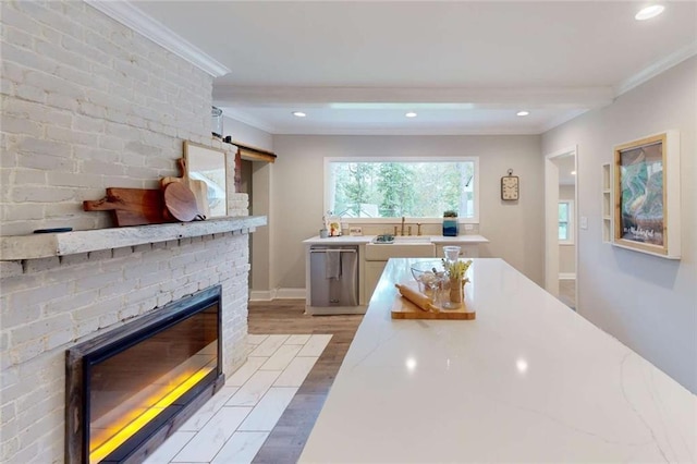 kitchen featuring stainless steel dishwasher, recessed lighting, light wood-style floors, crown molding, and a brick fireplace