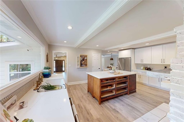 kitchen featuring a sink, ornamental molding, high end refrigerator, white cabinetry, and light wood-type flooring