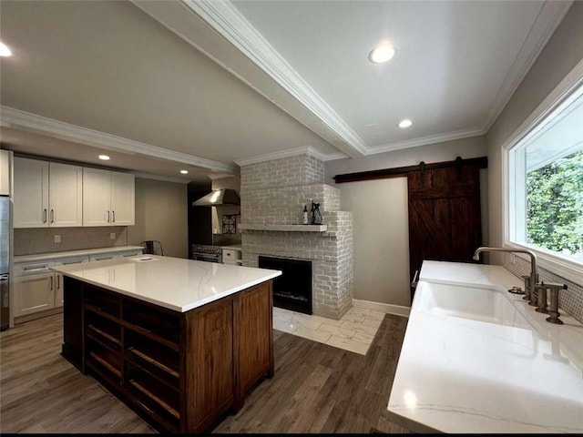 kitchen featuring backsplash, dark wood-type flooring, light countertops, a barn door, and ornamental molding