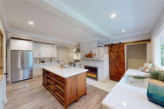 kitchen featuring wall chimney range hood, appliances with stainless steel finishes, crown molding, and light countertops