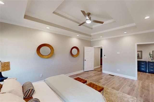 bedroom with a tray ceiling, baseboards, and light wood finished floors