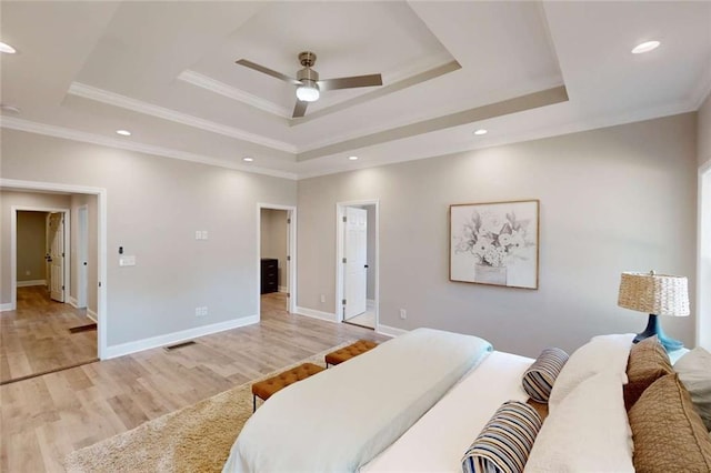 bedroom with light wood-type flooring, visible vents, a raised ceiling, and crown molding