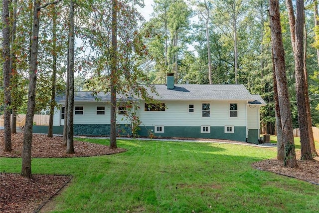 rear view of house with a yard, fence, and a chimney