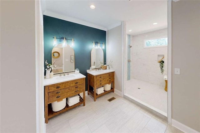 full bathroom with baseboards, visible vents, two vanities, a tile shower, and a sink