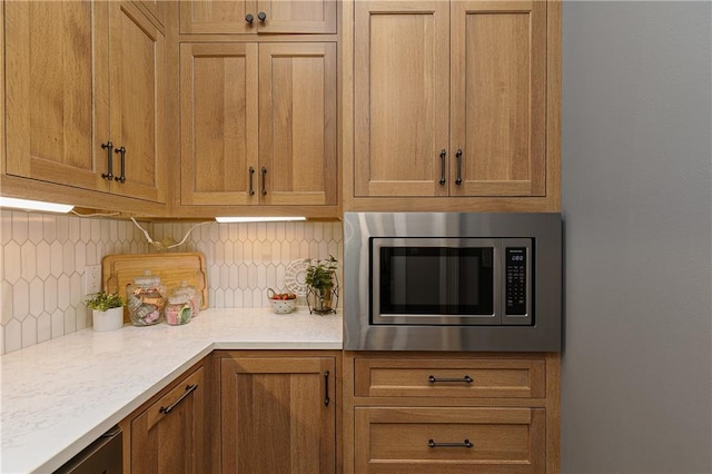 176 Nightwind Trce, Acworth, GA 30101 - kitchen featuring stainless steel microwave, tasteful backsplash, light countertops, and brown cabinets