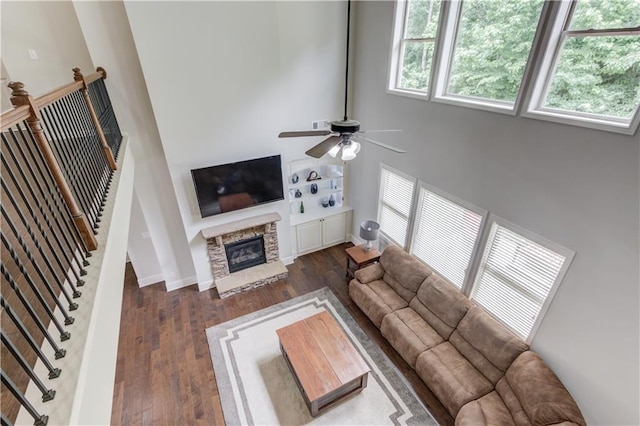 4241 Summer Breeze Way, Buford, GA 30518 - living area featuring a towering ceiling, a ceiling fan, wood finished floors, a stone fireplace, and baseboards
