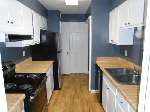 kitchen with stainless steel electric stove, sink, light wood-type flooring, extractor fan, and white cabinetry